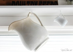 Classic farmhouse ironstone pitchers make a charming faux valance hanging under a window shelf - www.knickoftime.net