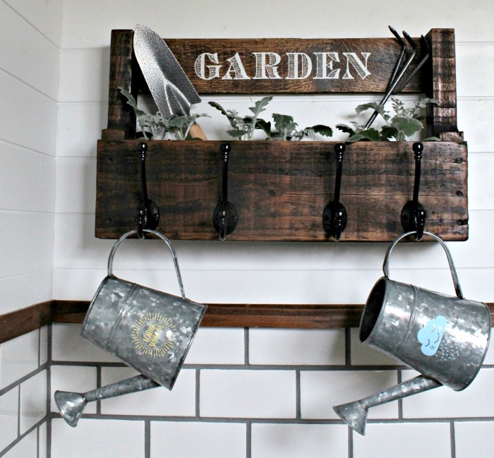 Hang your watering cans on an easy DIY pallet wood hanging garden planter. It offers storage and organization after the garden season!